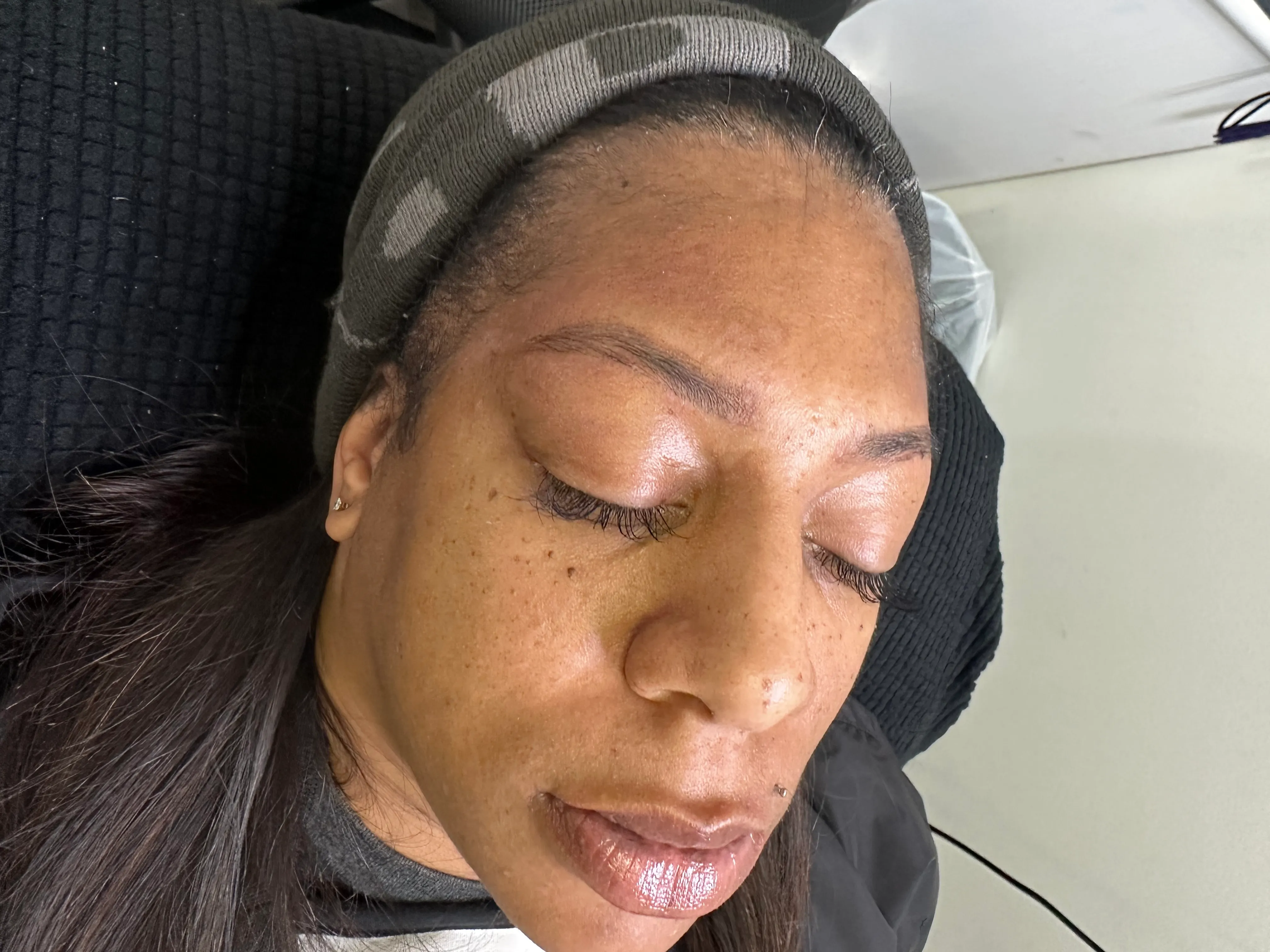 Client reclining with groomed brows, natural lashes, and glossy lips.