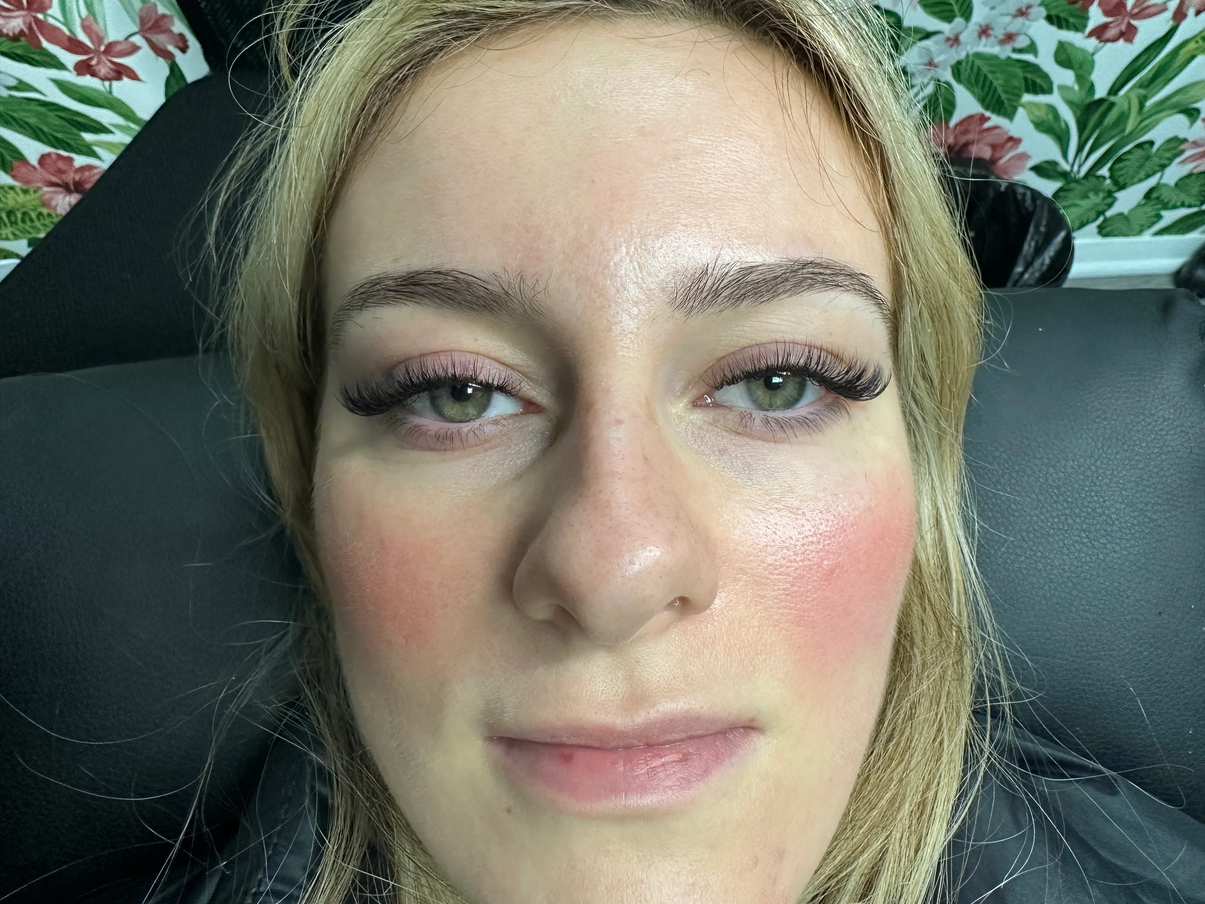 Close-up of dense curled volume lash extensions framing green eyes.